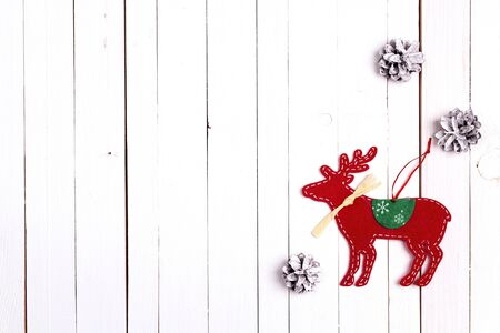 Christmas holiday background with decorative deer and snow painted pine cones on white wooden table. Space for text. Top view.の写真素材