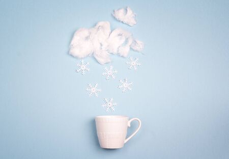 Snowfall in the coffee cup on blue background. Copy space. Winter weather concept.の写真素材