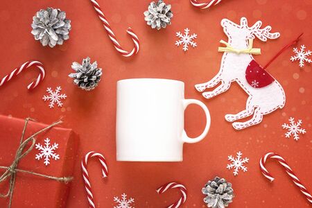 White coffee mug  with Christmas decorations on red background. Top view, flat lay. Space for text or design.の写真素材