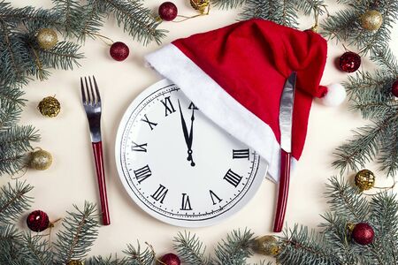 Clock plate with knife and fork and Christmas decorations on beige table. Christmas table setting. Top-down composition.の写真素材