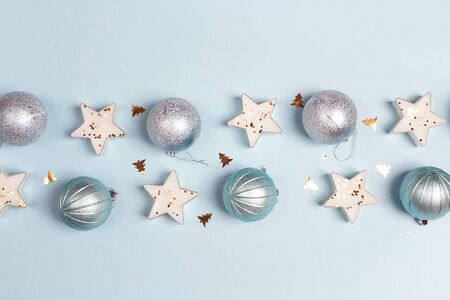Border of blue Christmas decorations with copy space on blue background. Top view, flat lay.