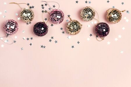 Border of Christmas decorations and copy space on a pink  background. Composition of mirror ballss and sparkles stars. Top view, flat lay.の写真素材