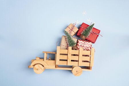 Wooden toy truck  with gift boxes and Christmas trees on blue background. Copy space, top view.の写真素材