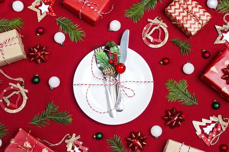 Festive table setting with cutlery and Christmas decorations on red cloth background.Top view....
