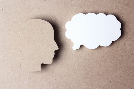 Head silhouette with speech bubble on brown paper background. Thoughts, dreams, conversation. Empty speech bubble with place for text.の写真素材