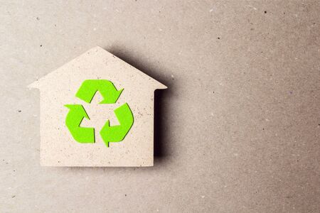 Ecological house with recycling symbol on brown paper background. Green eco home symbol.