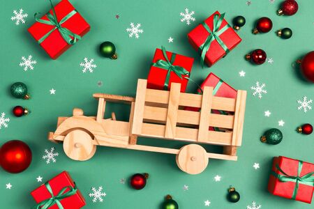 Wooden toy truck  with gift boxes and Christmas decorations on green background. Top-down composition.の写真素材