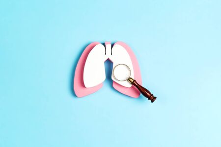 Prevention of pulmonary disease. Lung symbol with magnifier on a blue background. Healthcare and medicine concept.の写真素材
