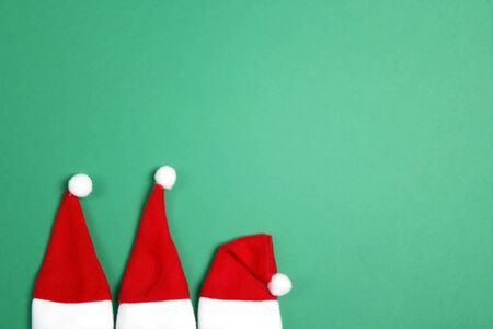 Three small santa hats on green background. Top view, flat lay, copy space.の写真素材