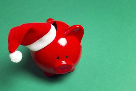 Piggy bank in santa hat on green background. Saving money for Xmas holidays.の写真素材