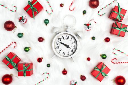 Christmas alarm clock with gift boxes and decorations on a white fur background. Christmas timer. Time to celebrate.の写真素材