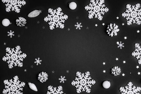 Winter holidays background with frame of snowflakes and white balls with copy space on black...