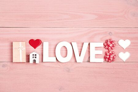 St. Valentines Day composition with word love, gift, miniature house and hearts on pink wooden background. Top down composition, flat lay,copy space.の写真素材