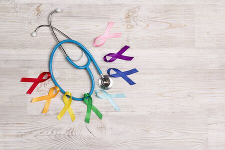 Colorful awareness ribbons with a stethoscope on wooden table. World cancer day concept, February 4....