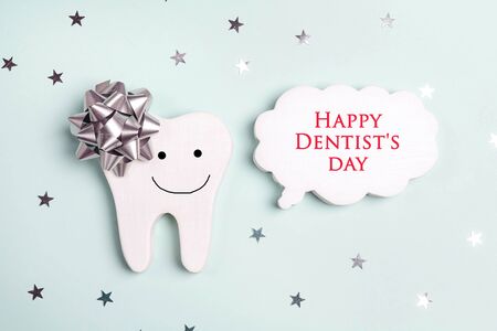 Dentist's Day greeting card with smiling tooth and speech bubble on a blue background. Copy space for text.の写真素材