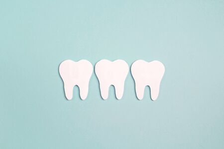 White paper teeth on blue background. Dental health concept. Dentist day concept. Flat lay, top view, copy space for text.の写真素材