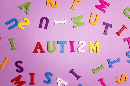 The word autism and multi-colored letters on a purple background. Autism Awareness Day. Autism Spectrum Disorder (ASD) concept.の写真素材