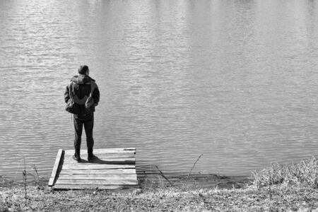 Alone man standing on the edge and staring at lake. Peaceful atmosphere in nature. Back view.の写真素材