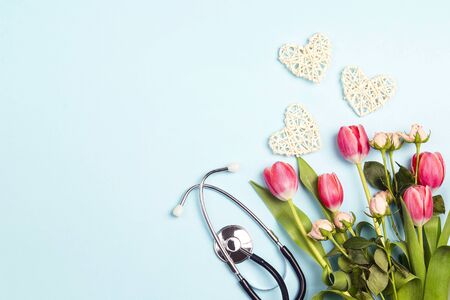 Bunch of tulips and roses with stethoscope on blue background. Top view with copy space. National Doctor's day. Happy nurse day. の写真素材