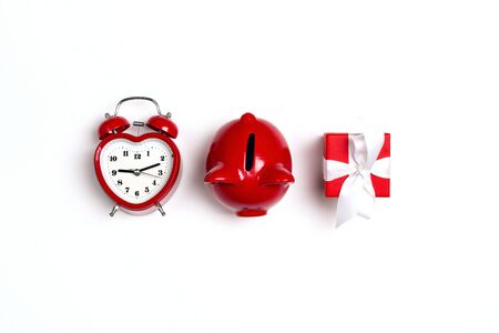 Alarm clock, piggy bank and gift on white background. Saving money for St. Valentines Day. Top down composition. の写真素材