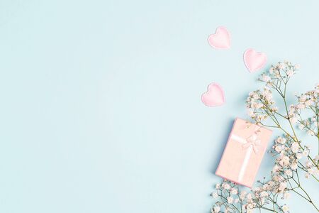 Festive blue background with small white flowers and a gift. Place for text. Flat lay, top view.の写真素材