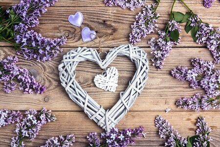 Lilac flowers with decorative hearts on old wooden background. Top view.の写真素材