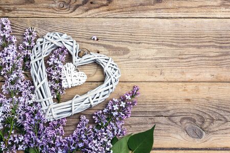 Lilac flowers with decorative hearts on old wooden background. Top view, copy space.の写真素材