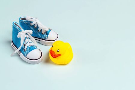 Cute baby sneakers and rubber duck on blue background. Copy space for text.の写真素材