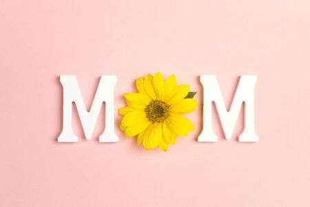 Word Mom with Yellow sunflowers on pink background. Mother's Day or women's day concept. Top view.の写真素材