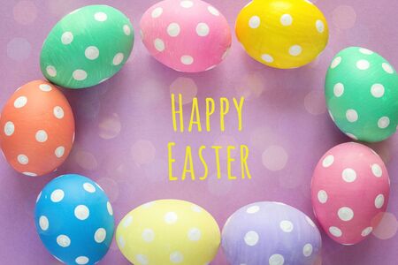 Frame of Easter eggs with Easter greetings on purple background. Top view.