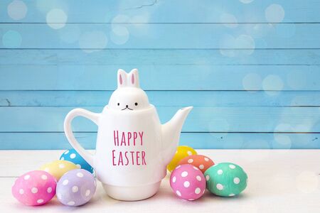 Kettle-hare with message Happy Easter and  Easter eggs on blue background.