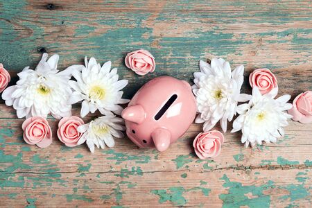 Piggy bank with flowers on old wooden background. Save money for spring holidays.の写真素材