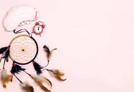 Dream Catcher with sleeping eye mask and alarm clock on pink background.  Copy space for text. Healthy sleep, rest, insomnia, tired concept.の写真素材