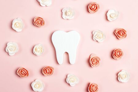 Tooth surrounded by roses on a pink background. Dentist day concept. Flat lay, top view.の写真素材