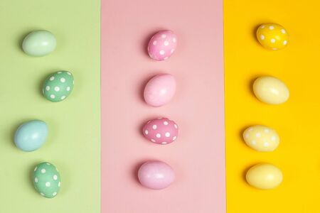 Green, pink and yellow Easter eggs on multicolored background. Flat lay top down composition.の写真素材