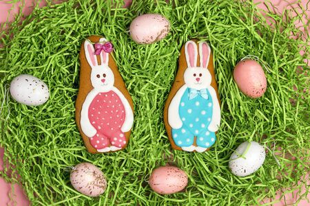 Easter homemade gingerbread cookies in shape of  bunny with eggs on a decorative grass.