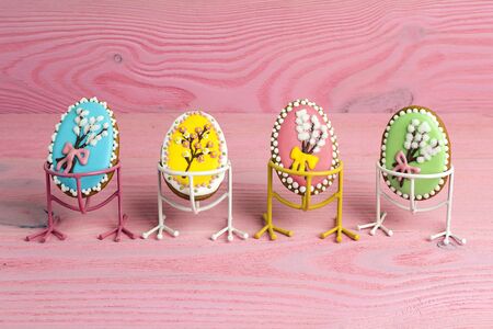 Funny Easter homemade gingerbread eggs on bird legs on pink background. Copy space.