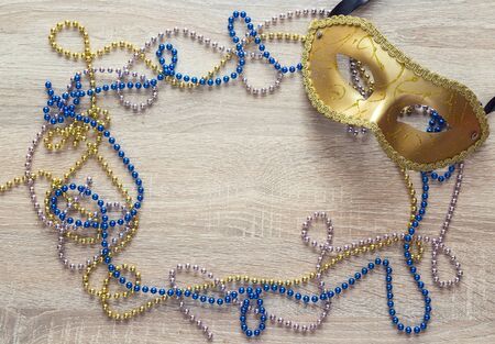 Mardi Gras background with golden mask, beads and copy space. Carnivale mask on a wooden background.の写真素材