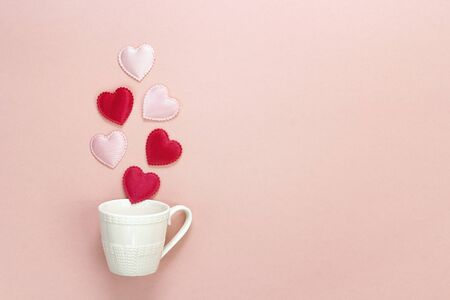 Coffee cup with hearts coming out of it  on a pink background. Space for the text.の写真素材