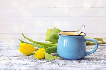 Blue coffee mug with yellow tulips on a white background. Space for text. の写真素材