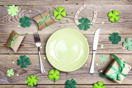 Festive table setting for St.Patrick's day with cutlery and lucky symbols on wooden table. Copy space, top view.の写真素材