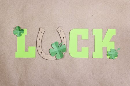 Word Luck with horseshoe and clover leaves on brown paper background. St.Patrick's day holiday symbol.の写真素材