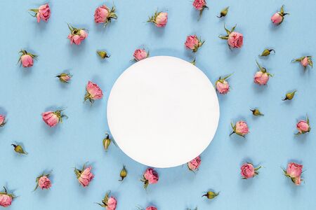 Round frame with pink roses on blue background. Flat lay, top view. Place for text.の写真素材