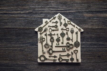 Handmade home symbol with vintage keys on wooden background. Home sweet home.