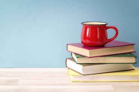 Stack of books and red mug against blue background.  Education background. Copy space for text.の写真素材