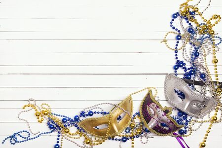 Festive Carnival background with masks, beads and copy space on wooden table. Carnivale mask on a white background.の写真素材