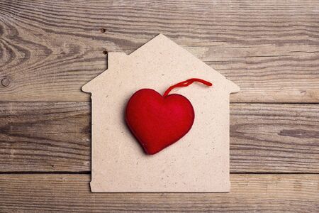Home symbol with red heart on old wooden background. Home sweet home.の写真素材