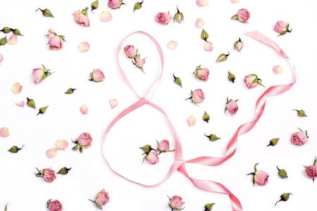 Eight of ribbons with pink roses on white background.Women's Day greeting message. Flat lay, top...