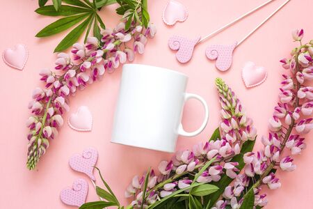 White coffee mug with lupine flowers and hearts on pink background. Space for text or design. の写真素材