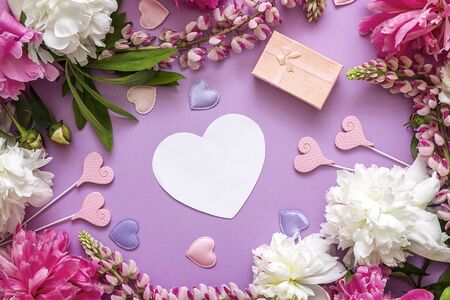 Blank paper heart-card with peonies, gift box and decorative hearts on a pink background. Copy...